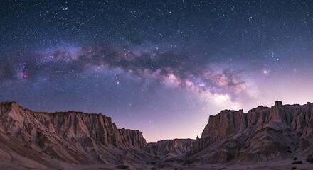 A stunning view of the Milky Way galaxy stretching across the night sky above a rugged desert landscape with canyons.