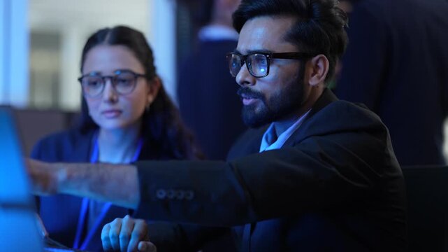 A lead AI engineer discusses a machine learning model's performance with a data scientist. They are analyzing computer simulations and AI algorithm outputs in a tech hub.