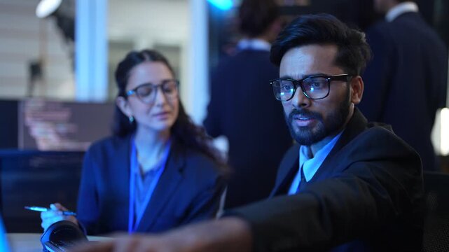 A lead AI engineer discusses a machine learning model's performance with a data scientist. They are analyzing computer simulations and AI algorithm outputs in a tech hub.