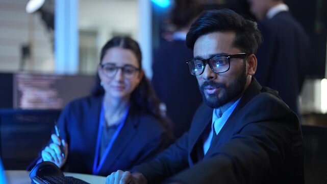 A lead AI engineer discusses a machine learning model's performance with a data scientist. They are analyzing computer simulations and AI algorithm outputs in a tech hub.