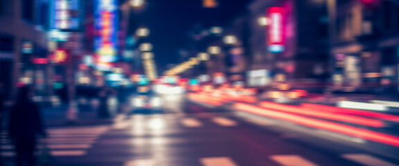 Blurred night city street scene with bright car light trails weaving around a lone pedestrian, capturing a cinematic, energetic urban atmosphere with glowing reflections and subtle movement.