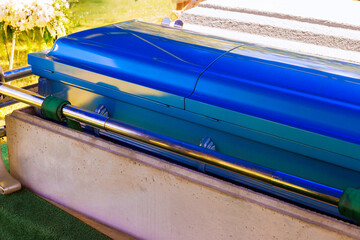 Bright blue casket is placed on gurney surrounded by greenery at memorial service in peaceful...