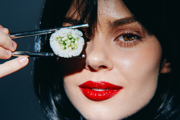 Elegant woman holding sushi with chopsticks, showcasing her beauty and passion for Japanese...