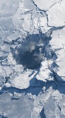 Fototapeta premium An aerial view shows a hole in a vast expanse of fractured, white-blue ice, revealing a dark water pool. Cracks radiate, creating an icy, broken landscape