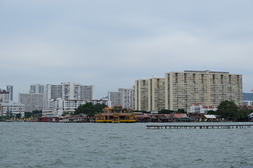 Obraz premium Colorful Chinese temple built on stilts above the sea, located along the waterfront in Penang, Malaysia, near traditional houses. 