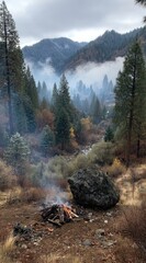 A scenic view of a mountain valley. A campfire burns in the foreground, with trees and mountains in the background, partially obscured by mist