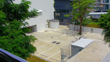 Open concrete lot bordered by leafy trees and buildings, softened with film grain texture and retro aesthetic tones.