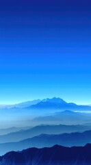 Fototapeta premium Serene view of hazy, blue mountain ridges receding into the distance beneath a vibrant, cloudless sky gradient from light to dark blue