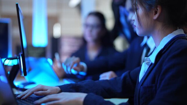 A group of female IT professionals discusses a project in their tech office. They are analyzing data and reviewing code, working as a team to solve a complex problem after hours.