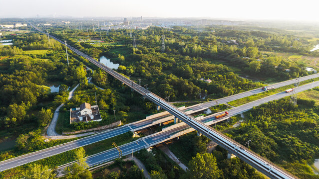An aerial shot shows several highways crossing each other amidst a lush green area, highlighting transportation and natural scenery.