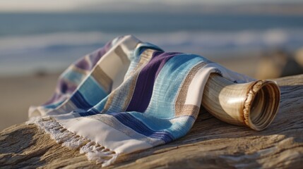 Shofar resting on wooden surface with colorful tallit prayer shawl outdoors, Rosh Hashanah or Hanukkah concept  