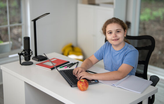 Kid studying at home with laptop and books. Child learn online using laptop at desk. Student with homework in a cozy room. E-learning on laptop. Kid tutoring at home. Interior with student and laptop. - Powered by Adobe