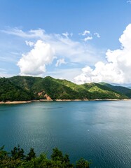 Obraz premium Scenic view of a lake surrounded by hills under a blue sky