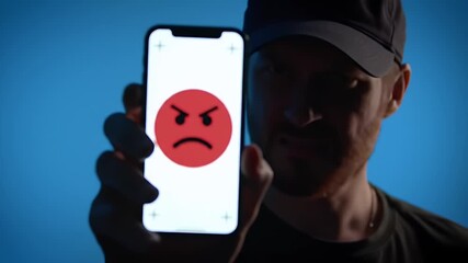 Man Shows Angry Emoji on Smartphone Against Blue Background - Powered by Adobe