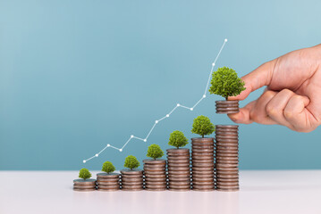 Interest rates,saving money, dividends and investment growth. A man put down coins with growing...