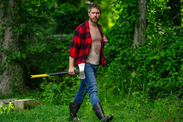 Hard working man with axe in forest. A bearded lumberjack with a large ax. Portrait of a brutal...