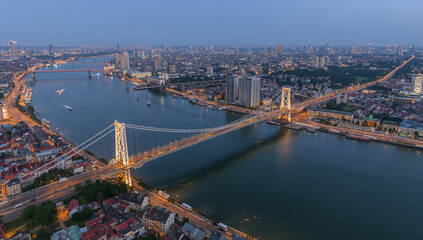Illuminated suspension bridge over wide river at dusk