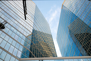 Fototapeta premium Modern glass skyscrapers reflecting blue sky in urban landscape