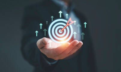Businessman holding digital target with arrow hitting center, symbolizing business success strategy leadership vision and achieving goals for growth and marketing.