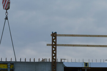 Obraz premium A construction site showcasing a crane lifting wooden beams against a cloudy sky.
