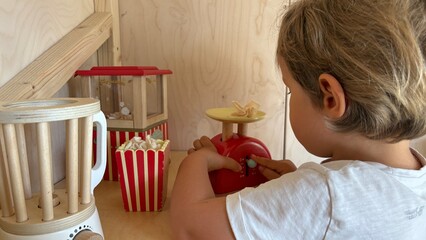 Child playing with wooden toy kitchen, popcorn and scale