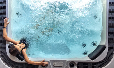 Girl in spa hot tub seen from above with bubbling water. Overhead view.