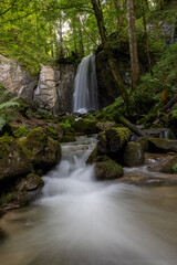 long exposure of a scenic waterfall in a mossy green valley in Switzerland