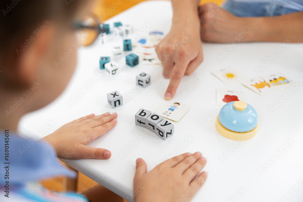 Poster child learning with alphabet blocks and flashcards at table