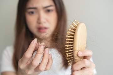 Close-up young woman brushing her hair and have many hair loss on the comb