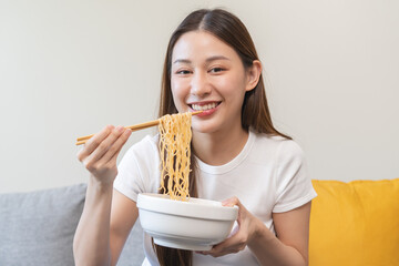 young woman eating instant noodles at home.