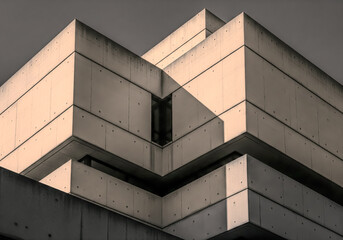 Geometric concrete building facade with strong shadows and light, abstract architectural detail, modern brutalist design, urban structure, sharp angles, minimalist aesthetic, contemporary exterior