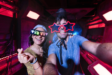 Young happy tourist couple taking funny selfie at k-pop photo booth in Seoul. Having fun in Korea...