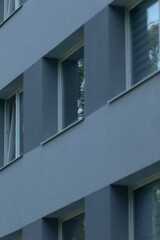 A close-up view of a modern building facade showcasing sleek gray panels and windows, reflecting contemporary architectural design.