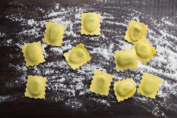Flat lay composition with raw ravioli on wooden table. Italian pasta