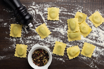 Fresh stuffed ravioli big size on wooden table with flour and eggs
