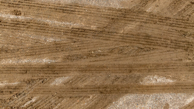 Aerial top view tire track on dirt sand mud, Texture of wet mud road with puddle and Tyre or tire track in countryside, Wheel tyre or tire track on mud, texture and background.