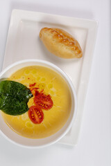 top view of a healthy pumpkin soup in a bowl with a spoon on a white plate with a pie