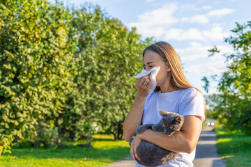 Fototapeta premium Woman holding a cat. Woman is allergic to cats. Allergy to cat fur.