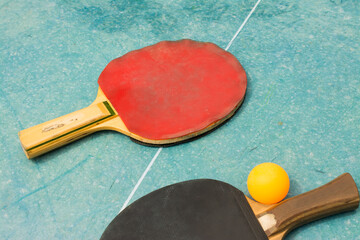 Ping pong paddles and ball on retro blue wooden background. Rackets ruined by time