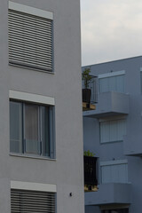 Close-up view of contemporary apartment buildings featuring stylish balconies and window shutters, set against a cloudy sky.