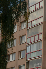 A close-up view of a modern apartment building featuring distinct red trim windows, showcasing contemporary architectural design with greenery in the foreground.