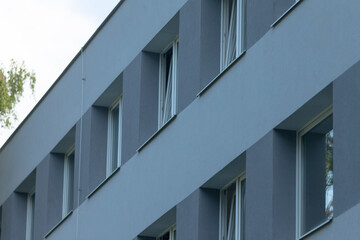 A close-up view of a contemporary gray building facade showcasing minimalist window designs and...