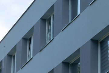 A close-up view of a contemporary building featuring a sleek grey exterior and aligned windows,...