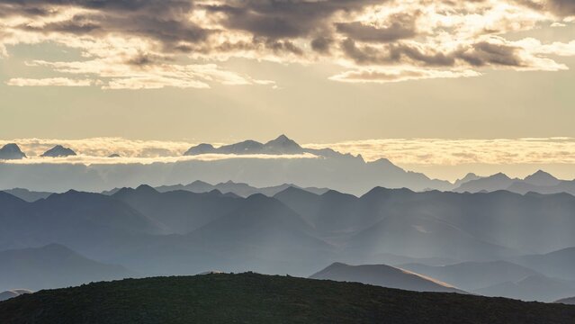 Layered mountain landscape with golden clouds at sunset