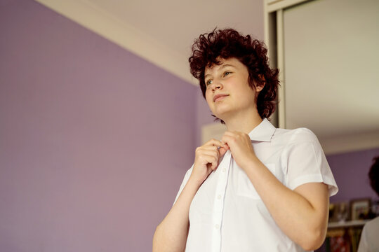 Teenage school girl buttoning white shirt. Back to school