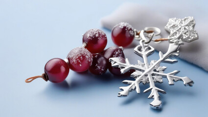 Silver snowflake pendant with red berries on light blue background, evoking festive winter mood
