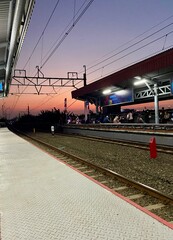 Fototapeta premium Railway Station at Sunset with Purple and Orange Sky