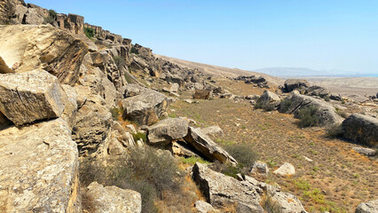 A rocky slope with huge boulders and rocks scattered over a large area. The outskirts of Gobustan...