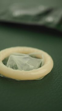 Condom displayed on green surface with packaging nearby
