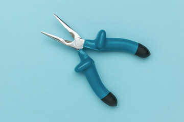 Blue Handled Needle Nose Pliers on Minimalist Light Blue Background for DIY and Craft Use